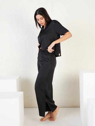a woman standing the wall wearing black fornt open half sleeve pyjama set