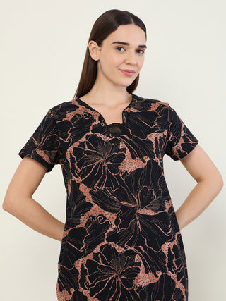 A woman wearing a black short-sleeved sleep dress with a floral print.