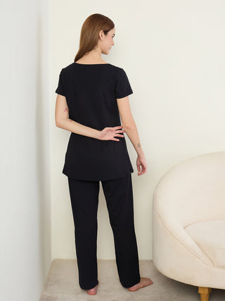Women's black t-shirt and pants set, from the back, with hands clasped behind the back.