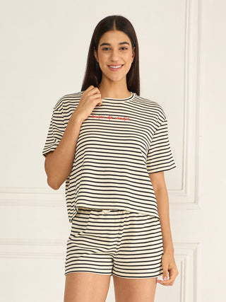 A woman wearing a striped pajama set with the text "bienfite de sangria" in red embroidery.