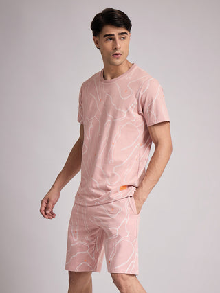 Men in a pink, printed sleepwear set, kneeling to the side.