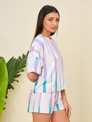 A woman poses in a tie-dye pajama set featuring purple and blue stripes.