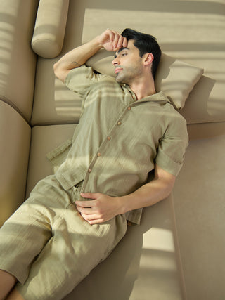 Men's light green linen pajama set, the model is lying on a sofa with his arm resting on his forehead.