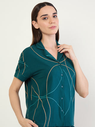 Women wearing a dark teal pajama top with an abstract line print, posed looking at the camera.