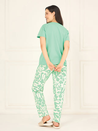 Women wearing a mint green t-shirt and patterned pants, posing with her back to the camera.