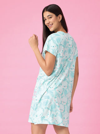 Women in a light blue nightgown with a cute cartoon print and a pink background, posing for the camera.