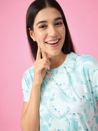 A woman with dark hair smiles, showing a dimple, while wearing a light blue sleep shirt with a pattern of cartoon seals.