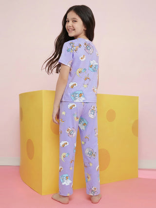 A young girl wearing lavender pajamas with a Tom & Jerry sleep-themed print, smiling happily while looking over her shoulder.