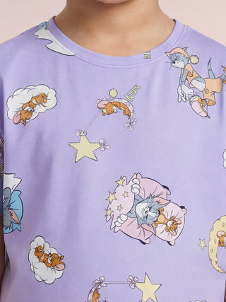 A child wears a light purple sleep shirt featuring sleeping Tom and Jerry characters amidst stars, clouds, and crescent moons.