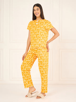 A woman poses in a yellow pajama set with a white bear print, featuring a short-sleeved top and pants, distinct from the previous image with its bear pattern and yellow hue.