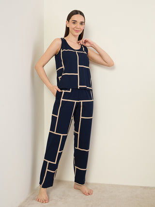 A woman stands in a blue sleeveless top and matching pants with a geometric cream-colored print.