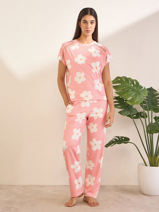 Women standing, wearing pink floral print short-sleeved pajamas with lace trim.