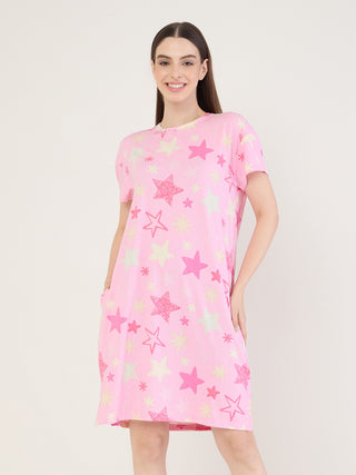 Women in a pink, star-print sleep dress, posing with hands in pockets.