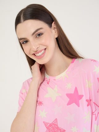 A woman in a pink, star-printed pajama set smiles at the camera.
