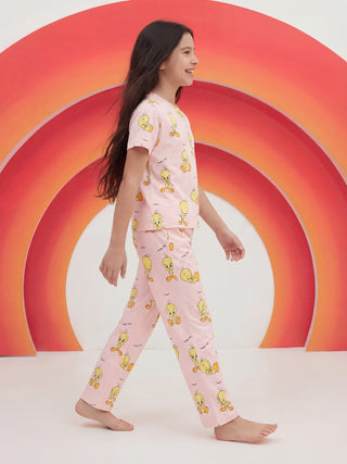 Smiling young girl striding in a pink matching pajama set featuring a Tweety Bird print.