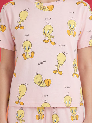 A woman's torso is shown wearing light pink short-sleeved sleepwear featuring multiple cartoon Tweety Birds in various poses and phrases like "I Tawt" and "Puddy Tat."