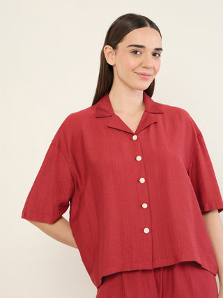 Women in a maroon pajama set, with a button-up collared shirt featuring unique floral buttons.