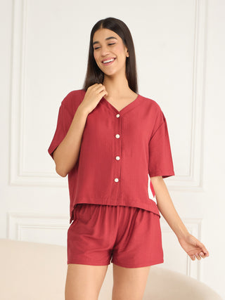 A woman poses wearing a red pajama set.