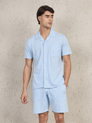 Men in a light blue printed short-sleeve pajama set standing, looking to the side.