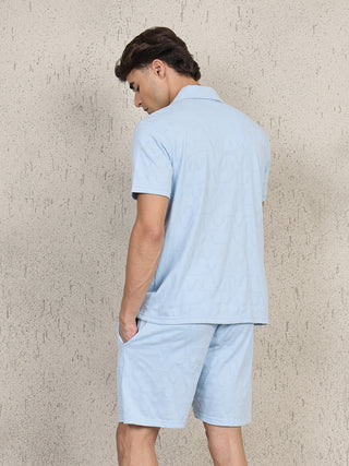 Men wearing a light blue short-sleeved polo shirt and matching shorts with a subtle geometric print, shown from the back.
