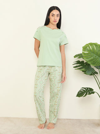 Women in a pale green t-shirt and matching geometric print pajama pants.
