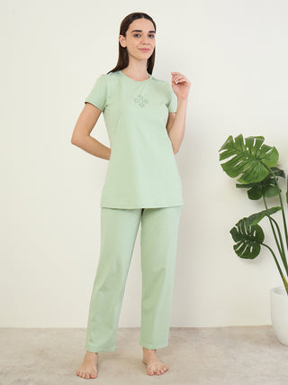 Women wearing a light green pajama set with delicate embroidery on the neckline, posing against a white background.
