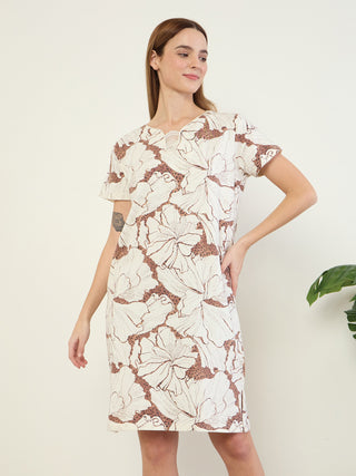 A woman poses in a short-sleeved, cream-colored dress with a large floral and leopard print.