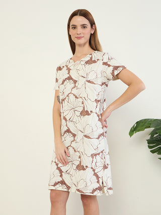 Women in a pose of standing, wearing a white short-sleeved dress with a floral print.