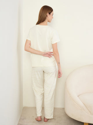 A woman wearing cream pajama set with dashed wave print.