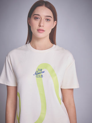 A woman in a white t-shirt with a lime green abstract print and blue text.