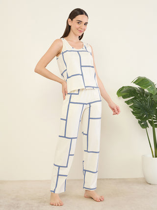 A woman in a cream, geometric print tank top and pants pajama set, posing with one hand on her hip.