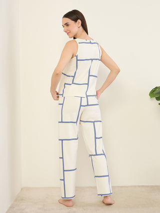 Women in a relaxed pose wearing a cream sleeveless top and matching pants with a blue geometric print.