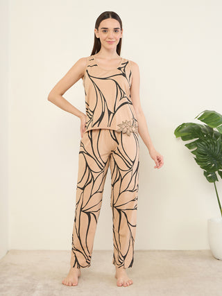 Women in a sleepwear set with a tan background and black abstract print, standing and posing with hands on hips.