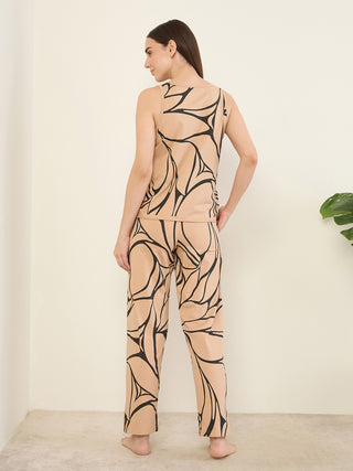 A woman stands with her back to the camera, wearing a beige sleeveless top and matching pants with a black abstract print.