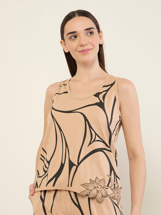 Women in a beige sleeveless top with a black abstract print and a floral embellishment.
