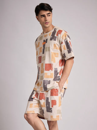 A man poses in a beige sleepwear set with a multi-colored abstract block print.